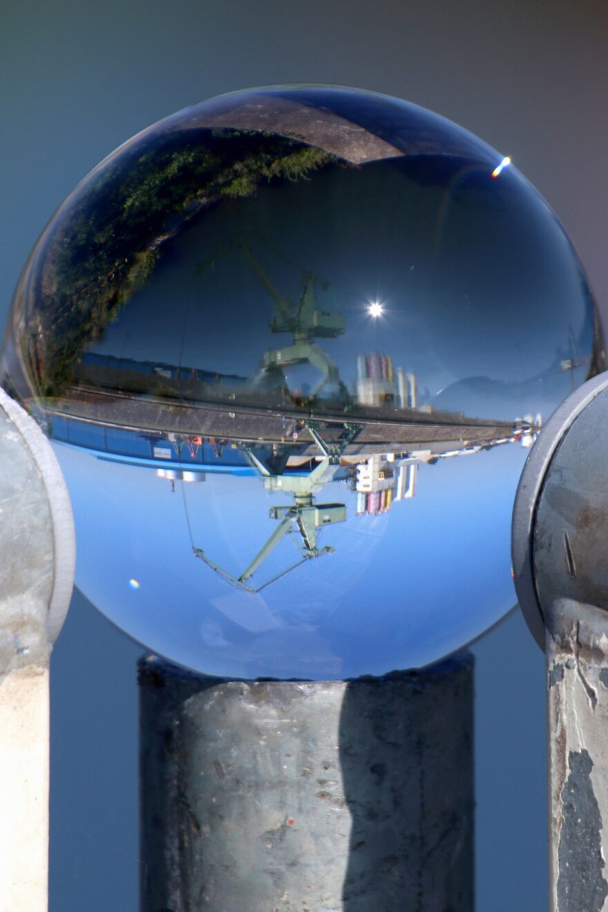 Glaskugel, in der sich ein Hafenkran spiegelt